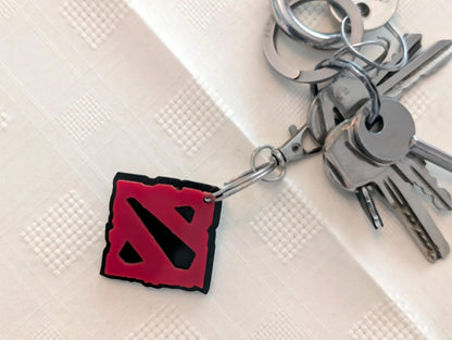 Metal keyring with red acrylic square charm and silver keys on textured surface