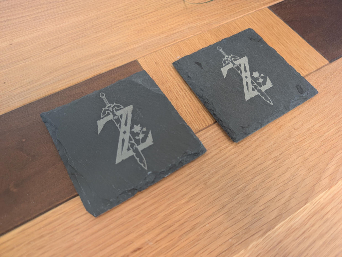 Engraved slate coasters with sword and Z design on wooden table