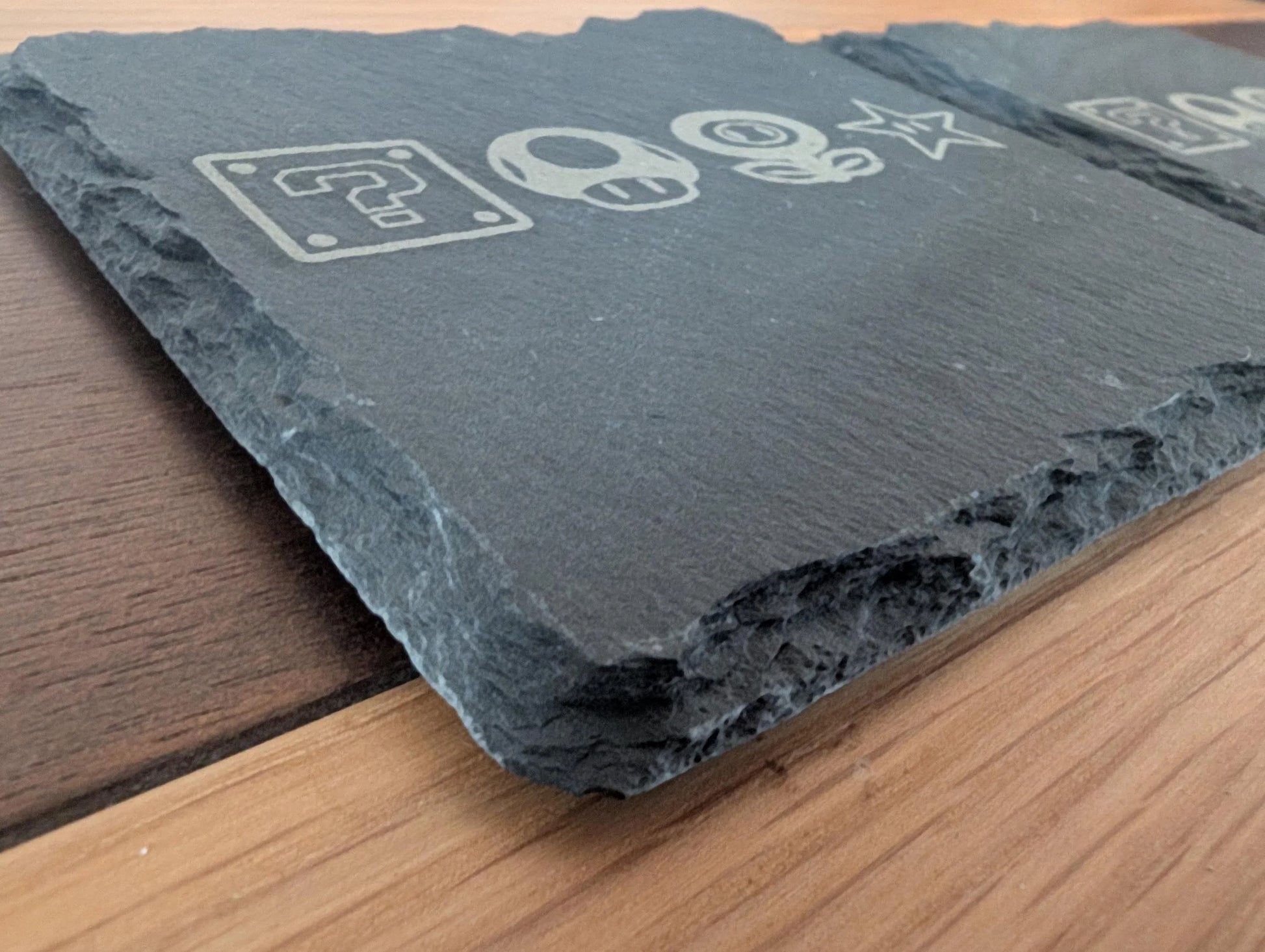 Engraved slate serving board with game-inspired icons on wood table