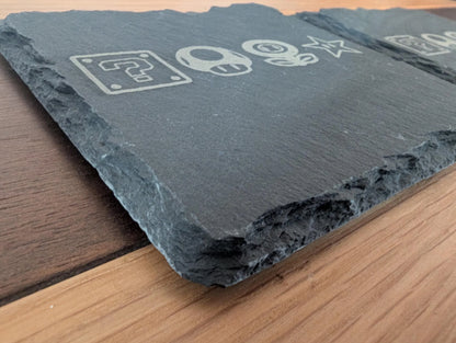 Engraved slate serving board with game-inspired icons on wood table