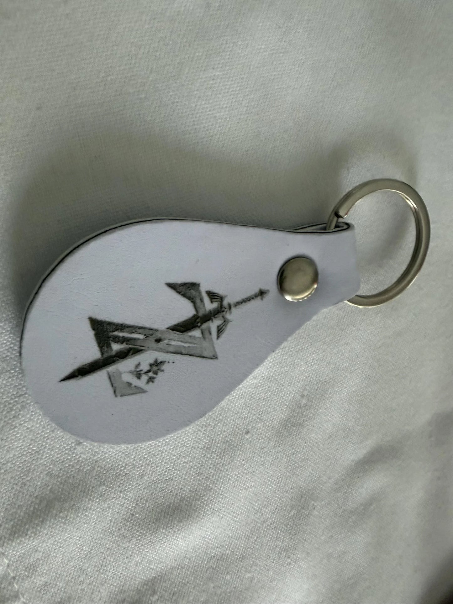 Custom white leather keychain with engraved abstract design on metal key ring