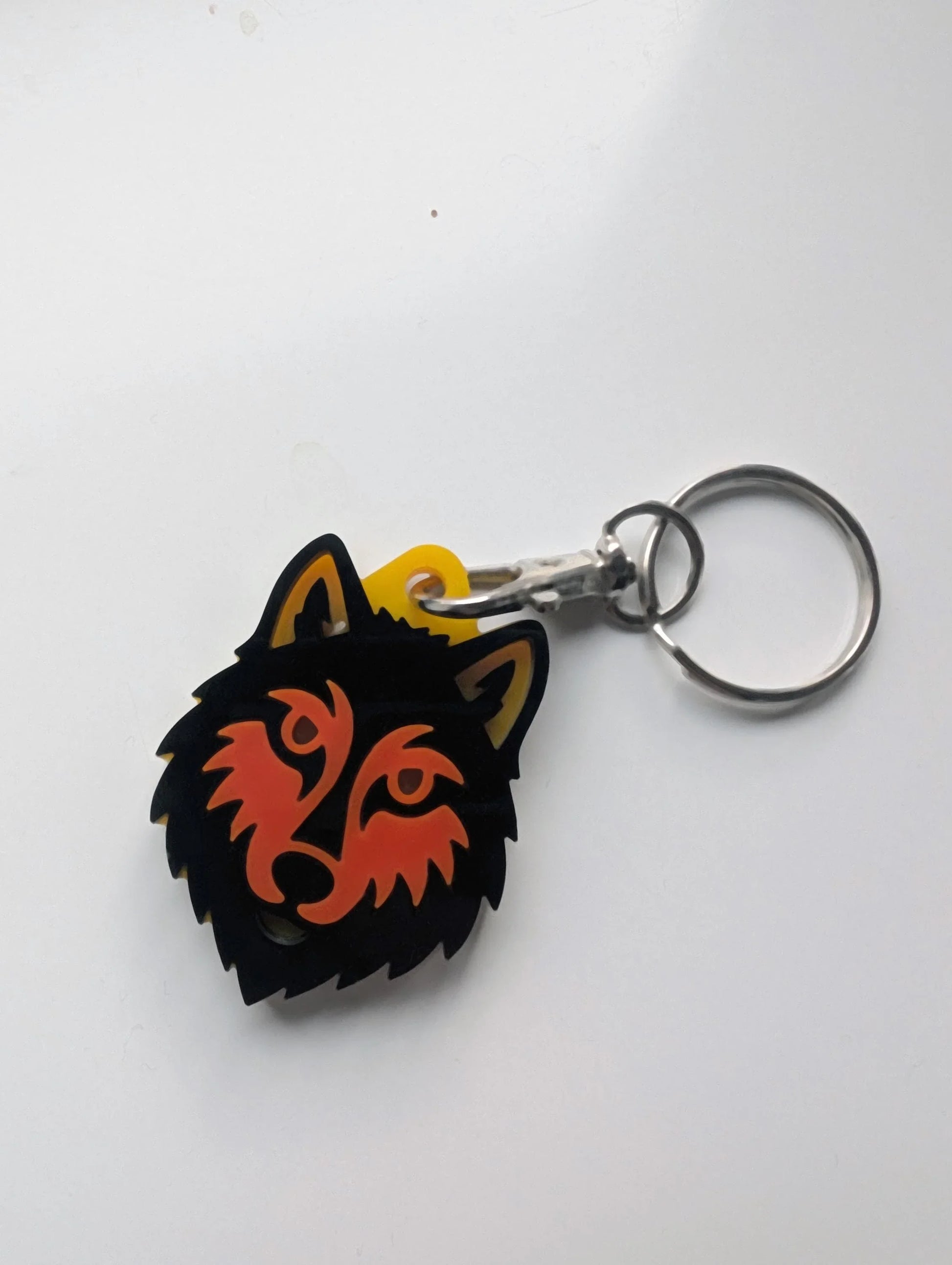 Acrylic wolf head keychain with orange and black layered design on metal key ring