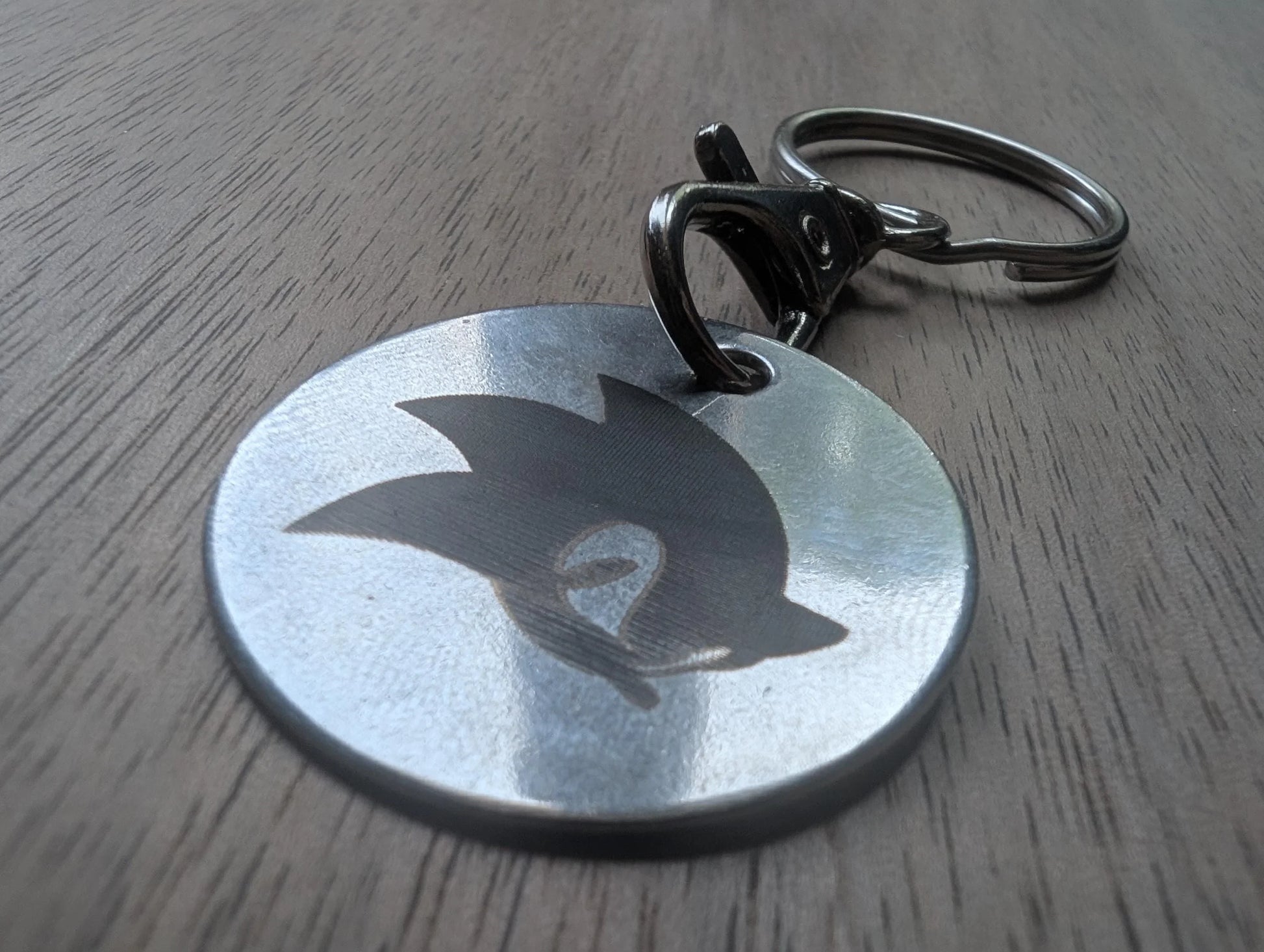 Custom engraved metal keychain with stylized silhouette on wood surface