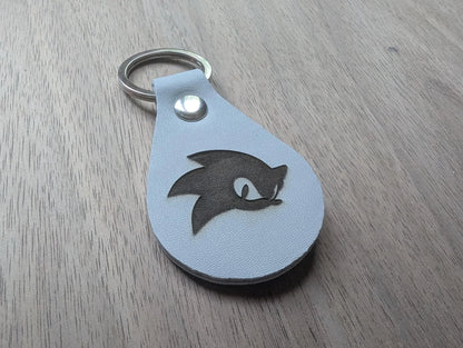Custom engraved leather keychain with a cartoon hedgehog face on wood background