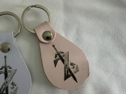 Custom leather keychain with engraved sword and geometric design on light pink background