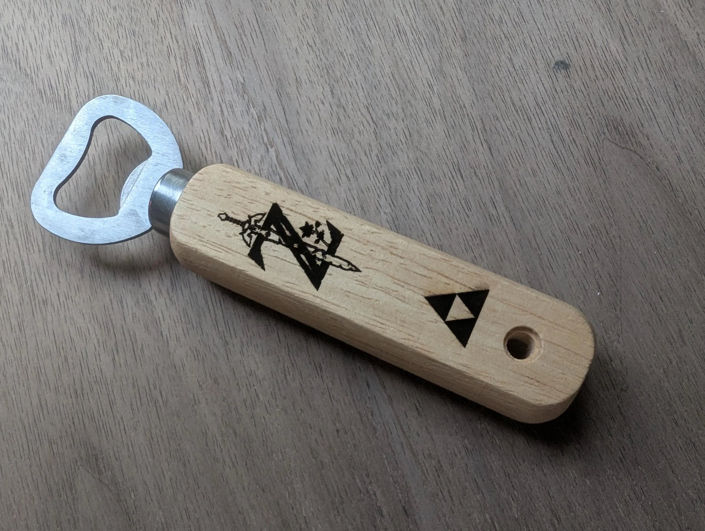 Wooden handle bottle opener with engraved geometric designs on a wood surface