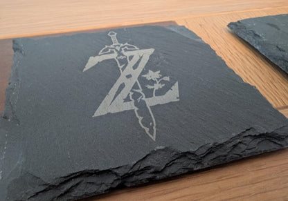 Engraved slate coaster with sword and leaf design on wood table