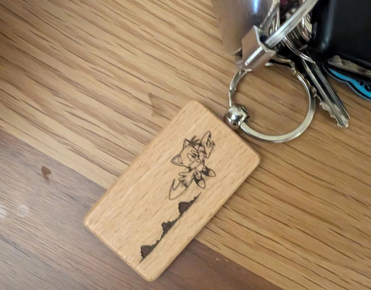 Custom engraved wood keychain with floral design on metal keyring, on wood table