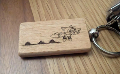 Laser engraved wood keychain with cartoon fox design and metal ring on wood surface