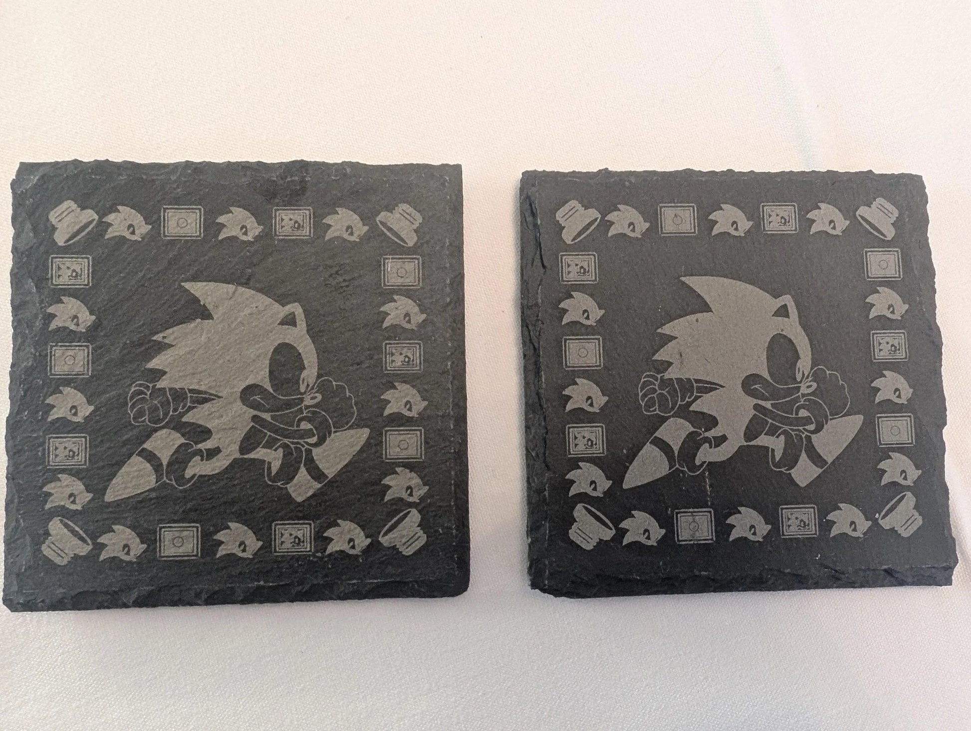Custom engraved slate coasters with running character design and retro gaming motifs