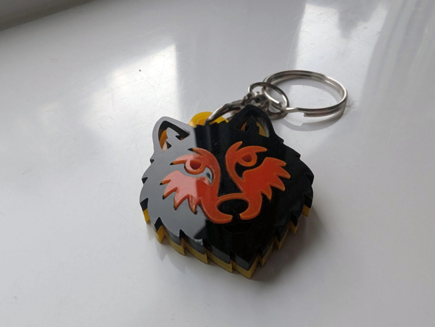 Custom acrylic wolf head keychain with layered black, orange, and yellow design on metal ring