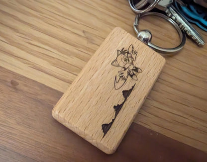 Custom engraved wood keychain with cartoon cat design, metal key ring, on wooden surface