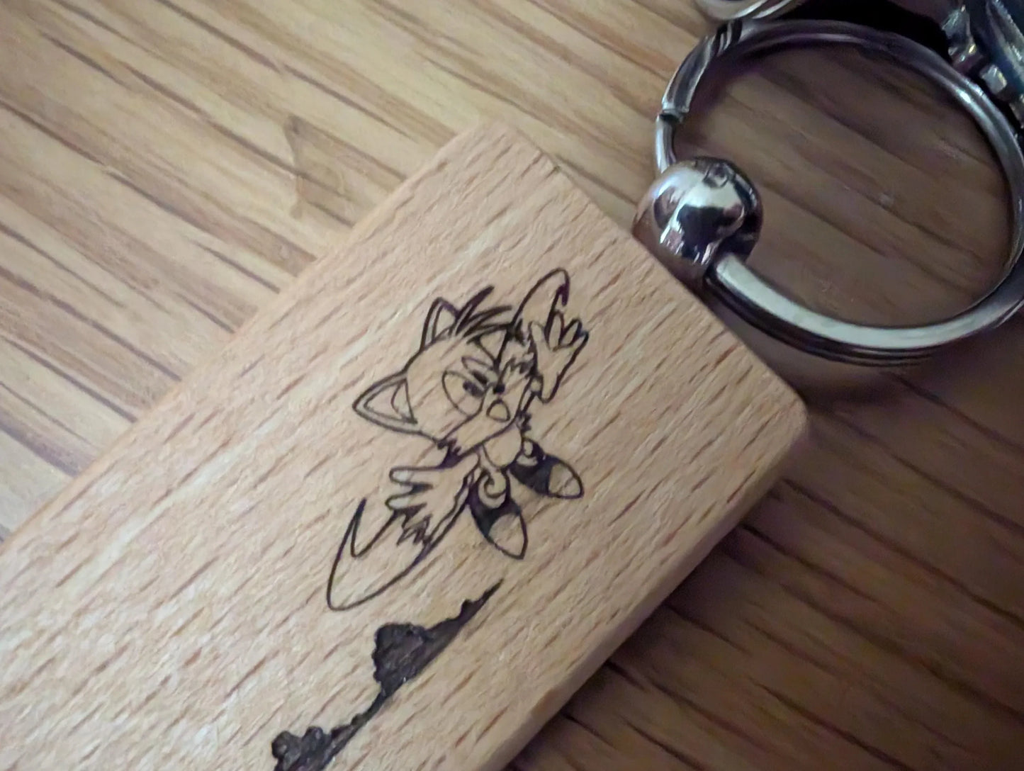 Custom engraved wood keychain with cartoon cat design on polished wood surface