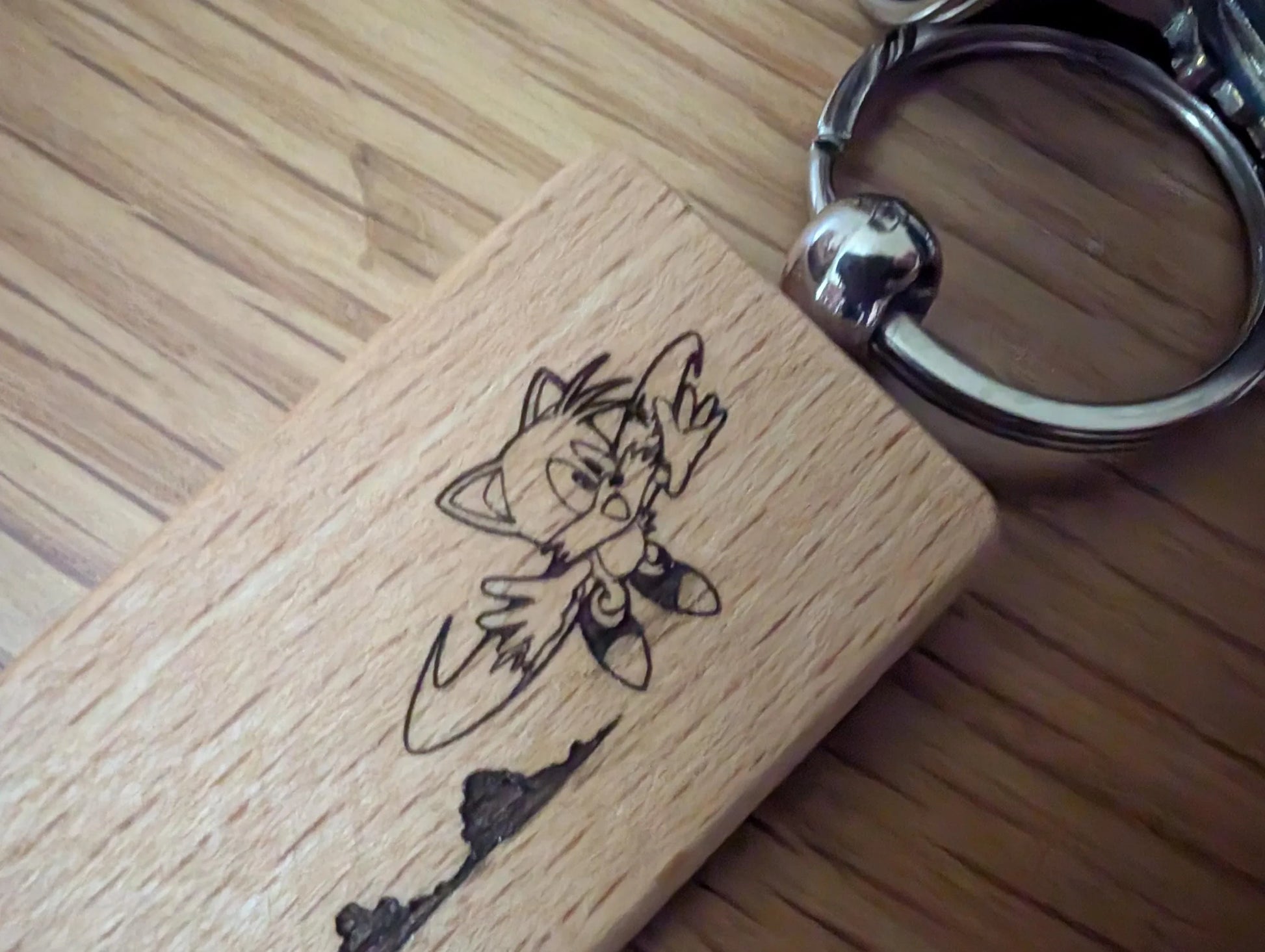 Custom engraved wood keychain with cartoon cat design on polished wood surface