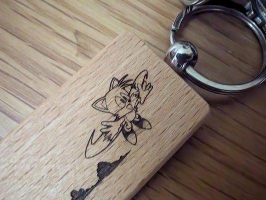 Custom engraved wood keychain with cartoon cat design on polished wood surface