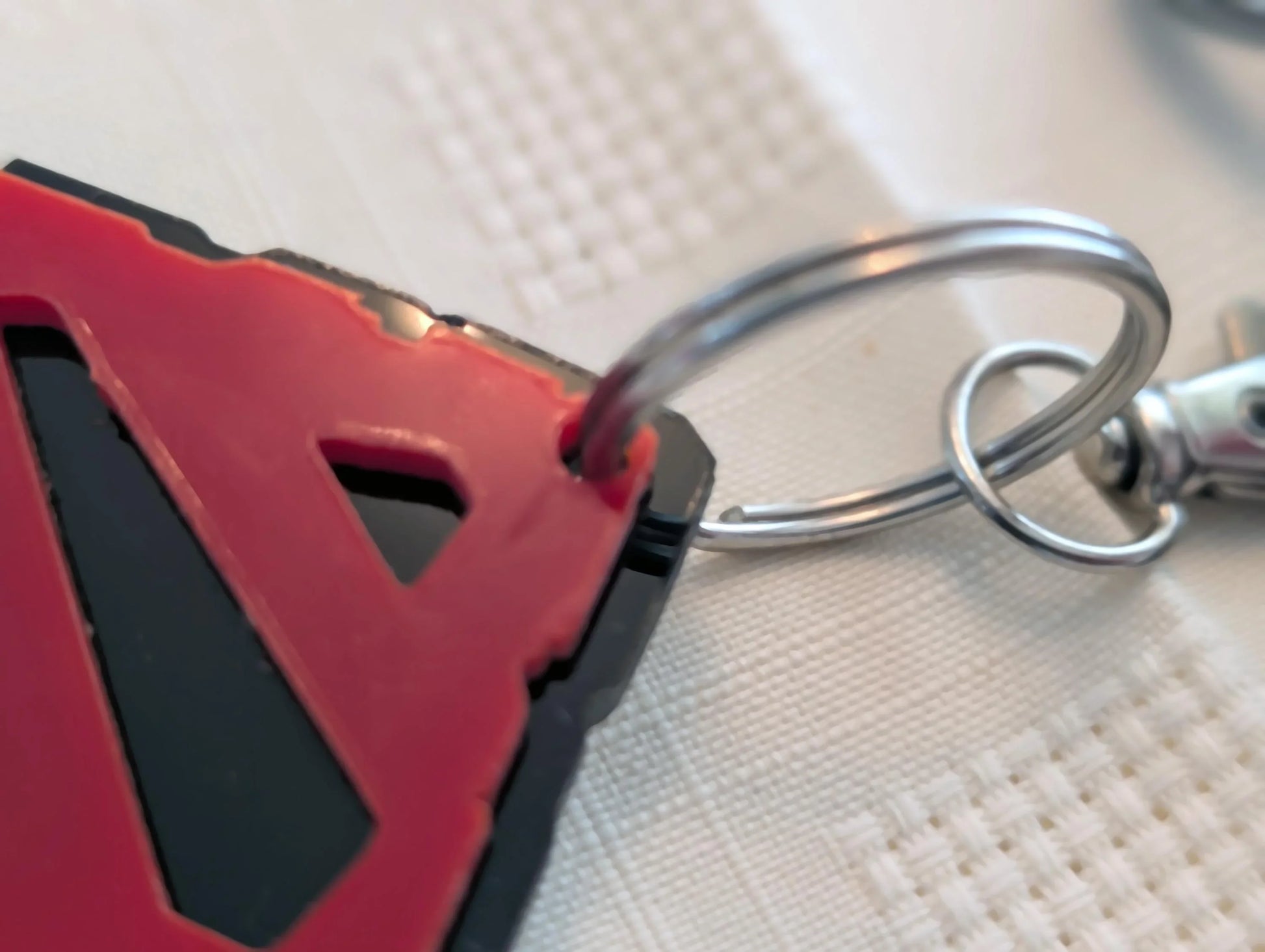 Close-up of a custom acrylic keychain with red and black geometric design on a metal key ring