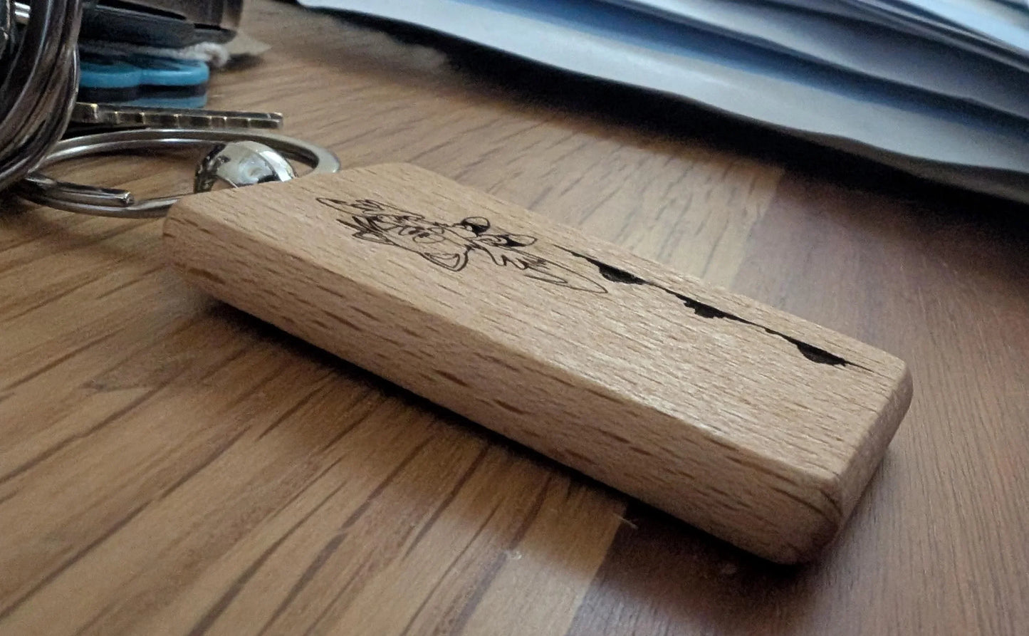 Engraved wooden keychain with animal design on a wood surface