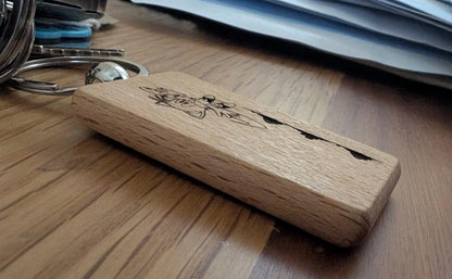 Engraved wooden keychain with animal design on a wood surface