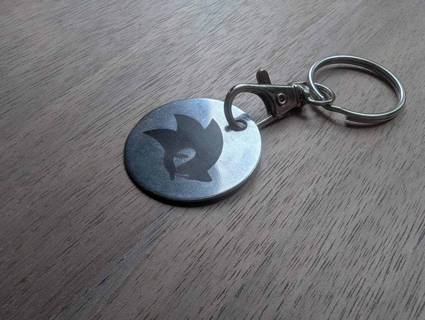 Custom engraved metal keychain with round tag on wooden surface