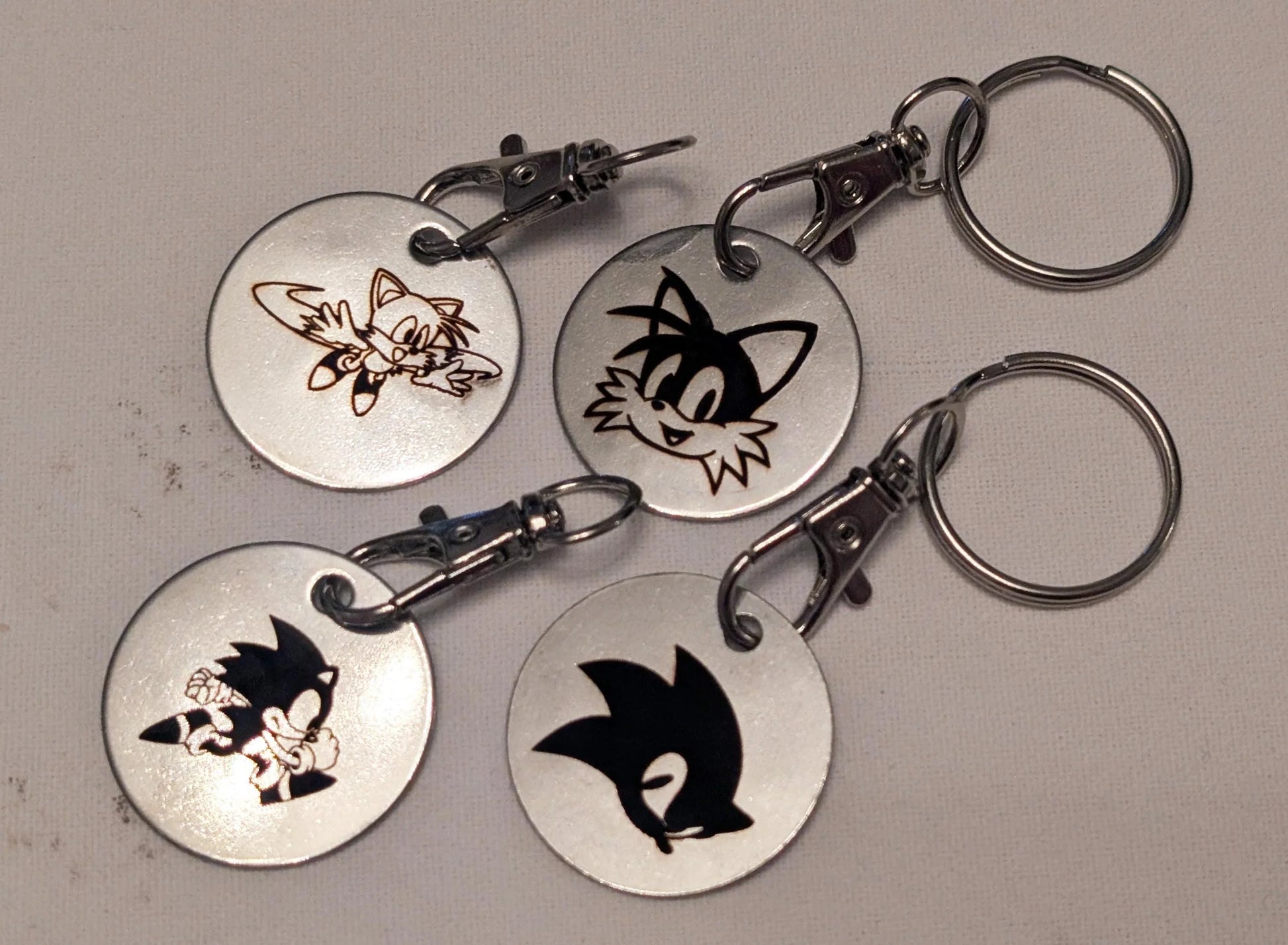 Set of four custom engraved metal keychains with cartoon character designs on round silver tags