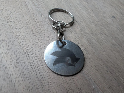 Round custom metal keychain with engraved design on wood surface