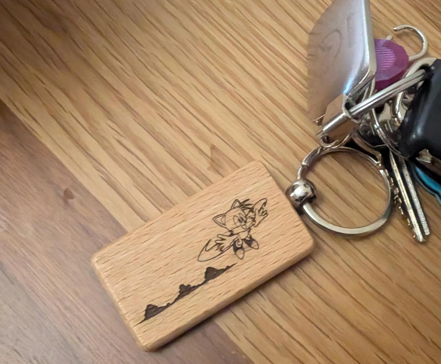 Custom wood keychain with engraved cartoon character and mountain design on wood surface