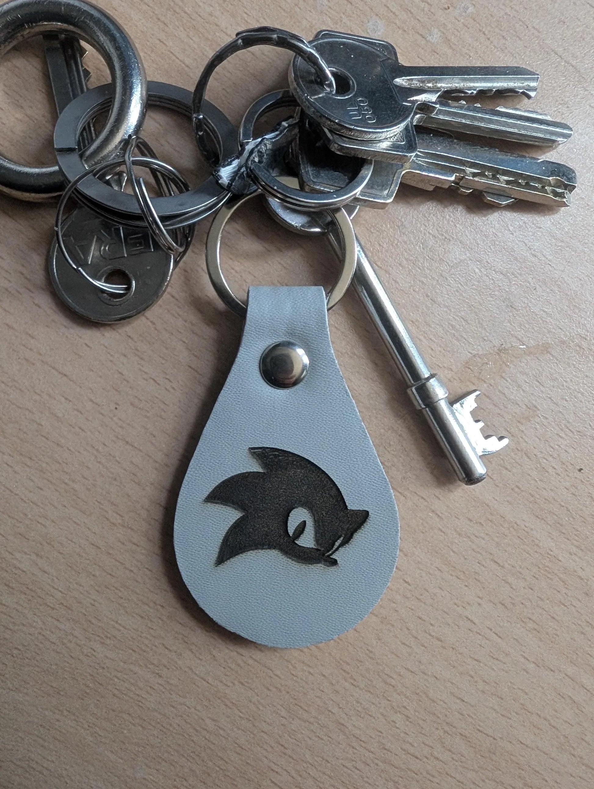 Custom engraved metal keychain with a character silhouette on a keyring, on wood surface