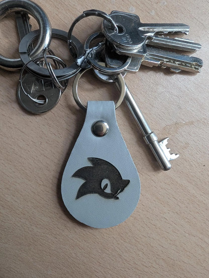 Custom engraved metal keychain with a character silhouette on a keyring, on wood surface