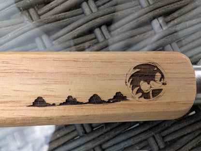 Custom wooden handle with laser-engraved cartoon character and landscape design