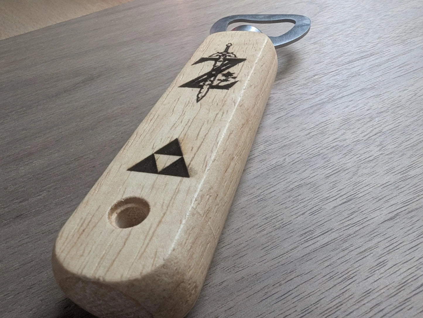Wooden handle bottle opener with engraved sword and triangle symbols on a wood surface