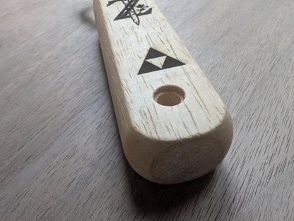 Wooden handle with laser-engraved geometric symbols on light wood surface