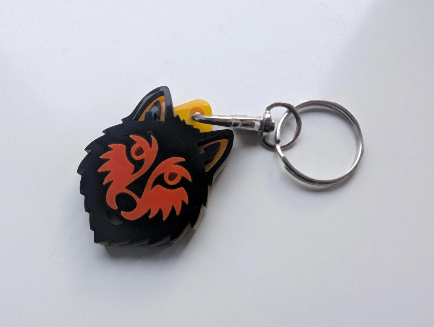 Acrylic keychain with black and orange wolf head design on metal key ring