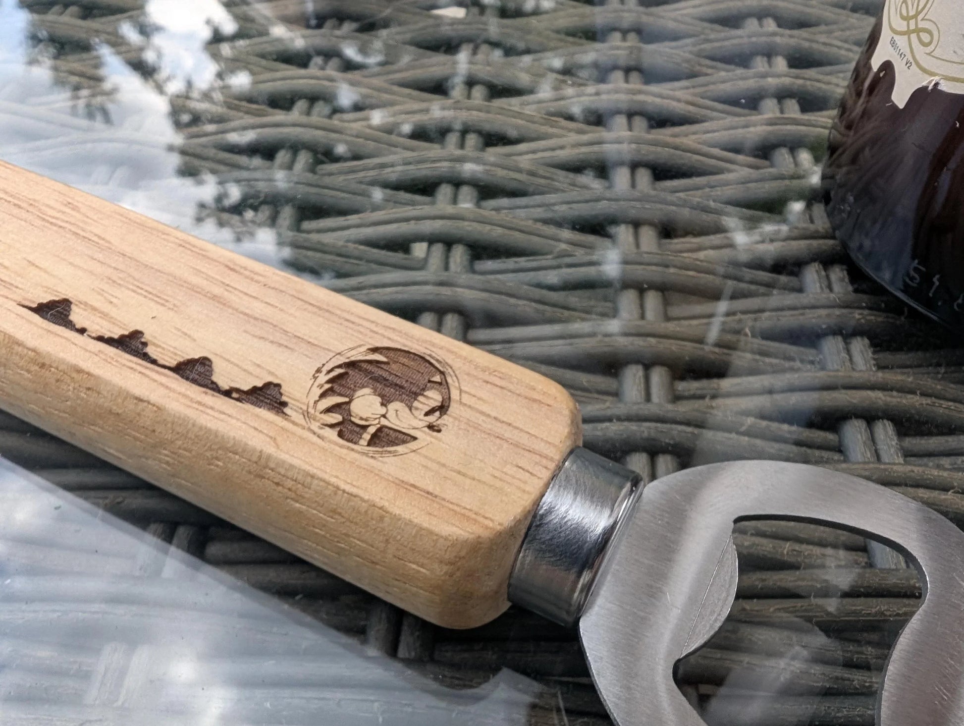 Custom engraved wooden handle bottle opener with mountains and bird design on outdoor table