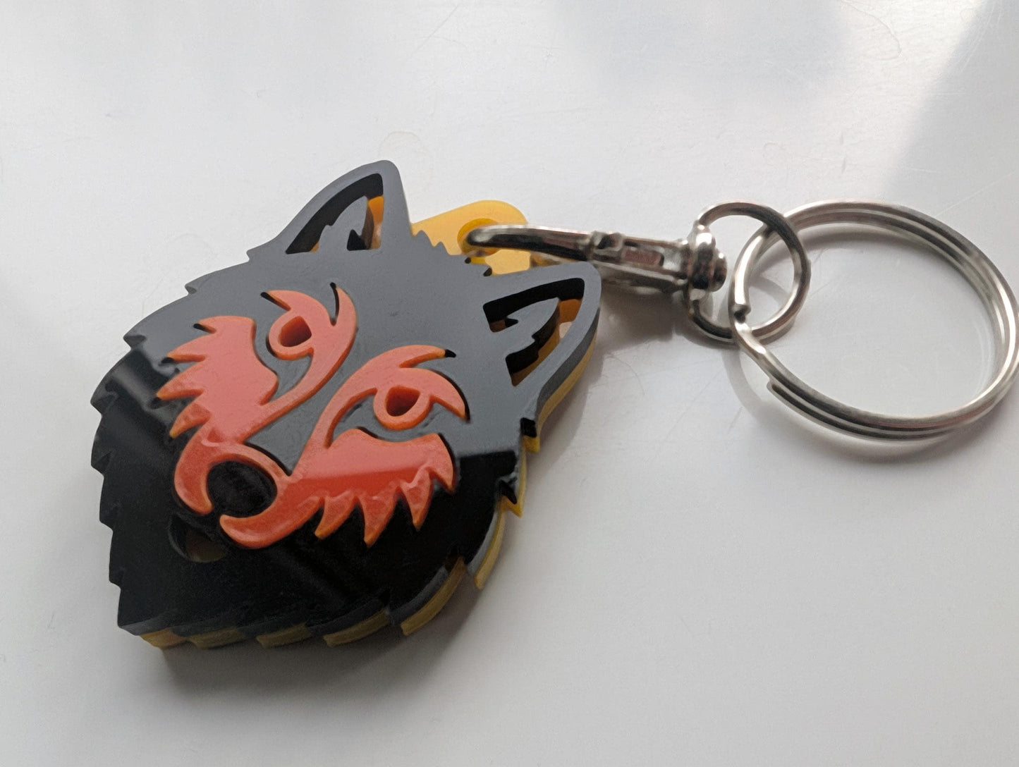 Acrylic wolf head keychain with black and red layered design on metal ring