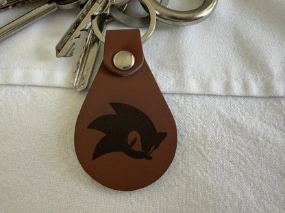 Brown leather keychain with engraved graphic, metal rivet, attached to silver keys