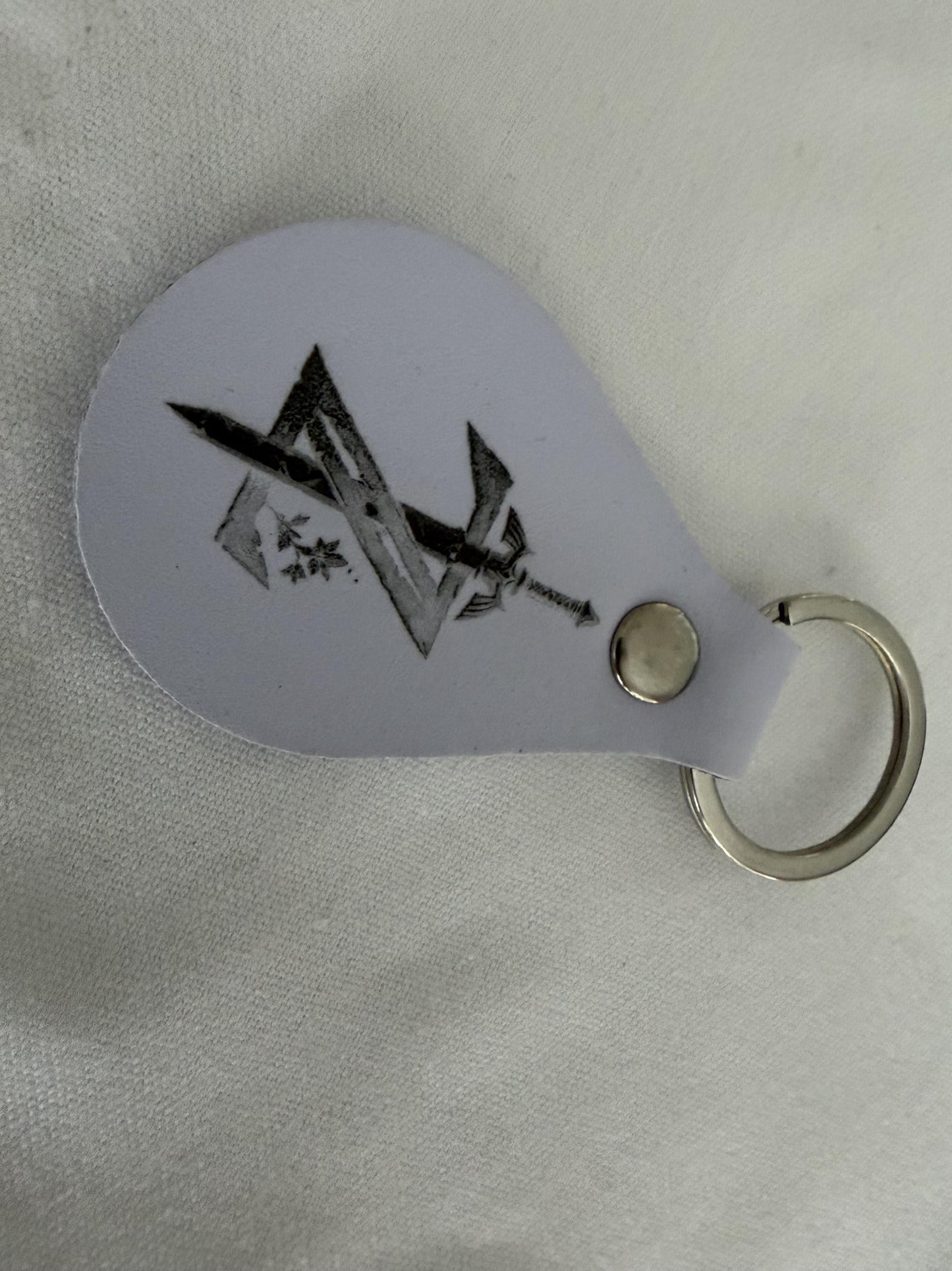 Custom engraved metal keychain with black geometric and sword design on white background