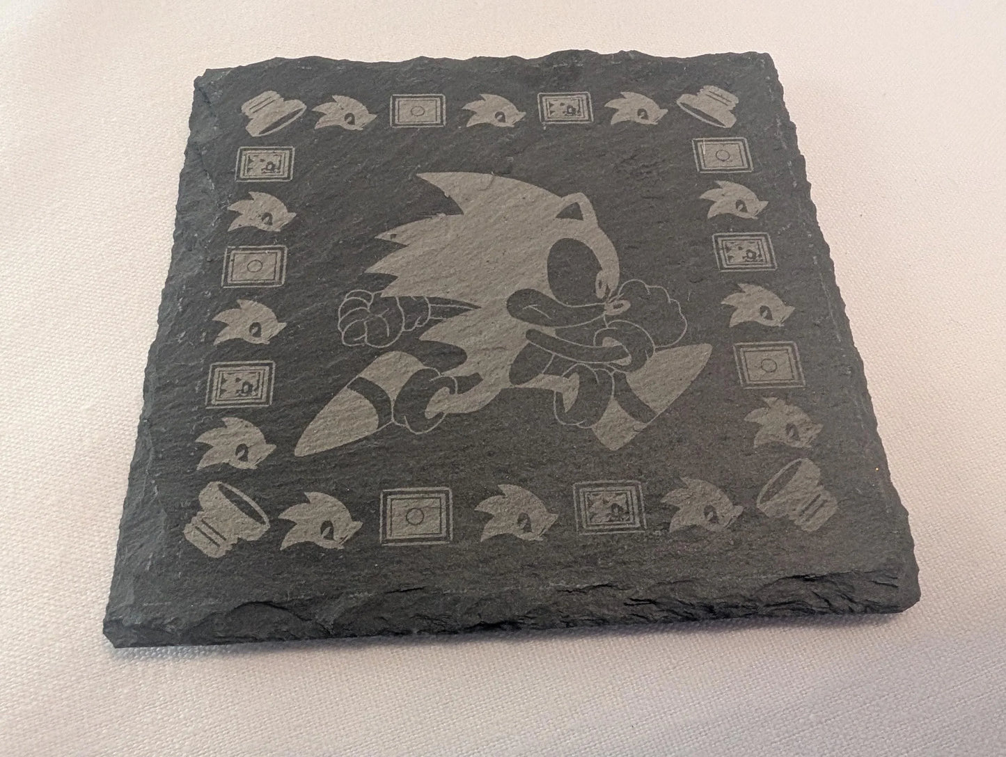Engraved slate coaster featuring a running cartoon hedgehog and gaming icons, custom made