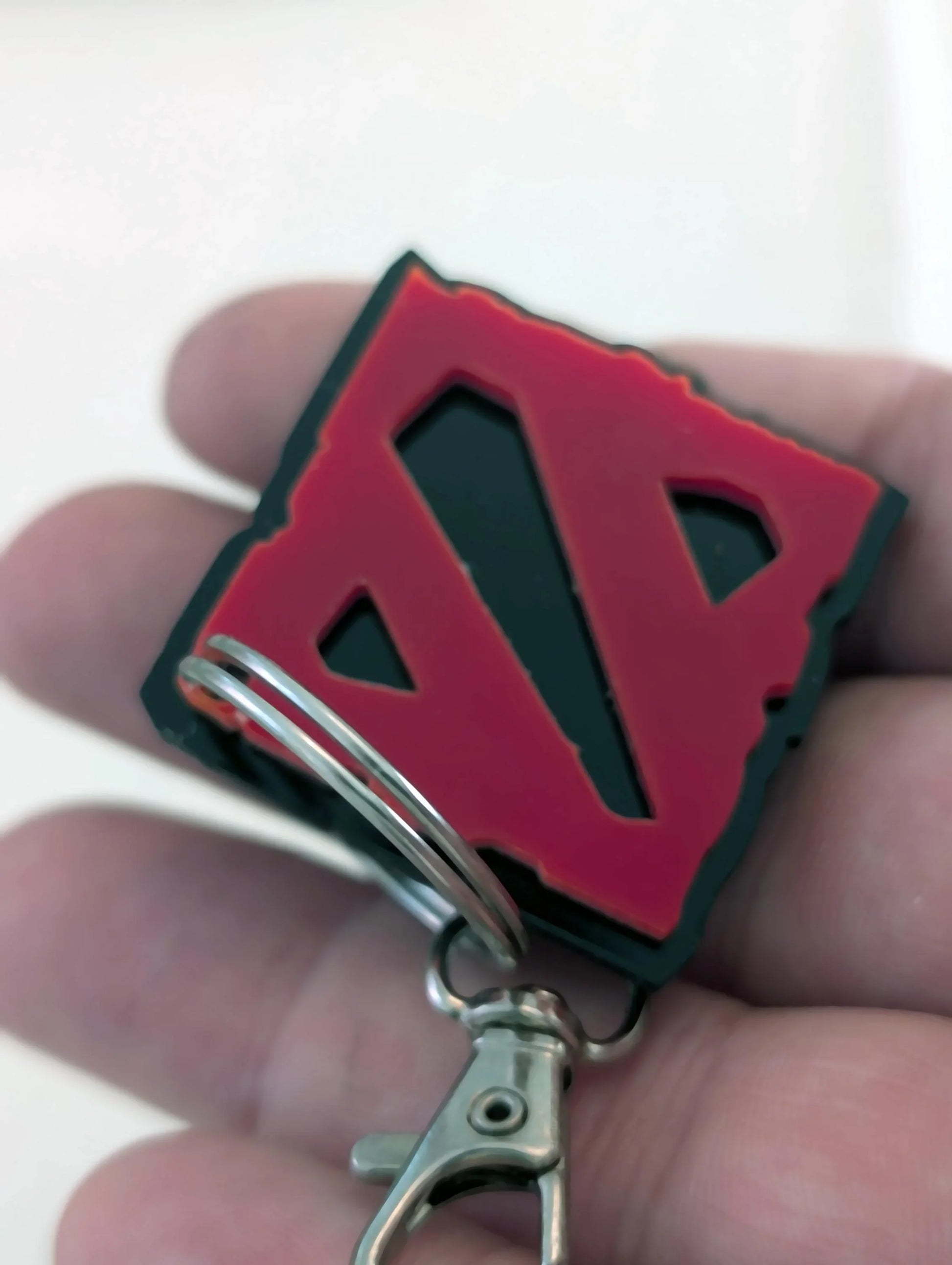 Hand holding a custom square keychain with red geometric design, metal key ring and clasp
