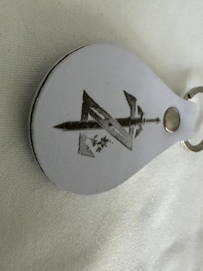 Custom white leather keychain with engraved sword and geometric design on metal ring