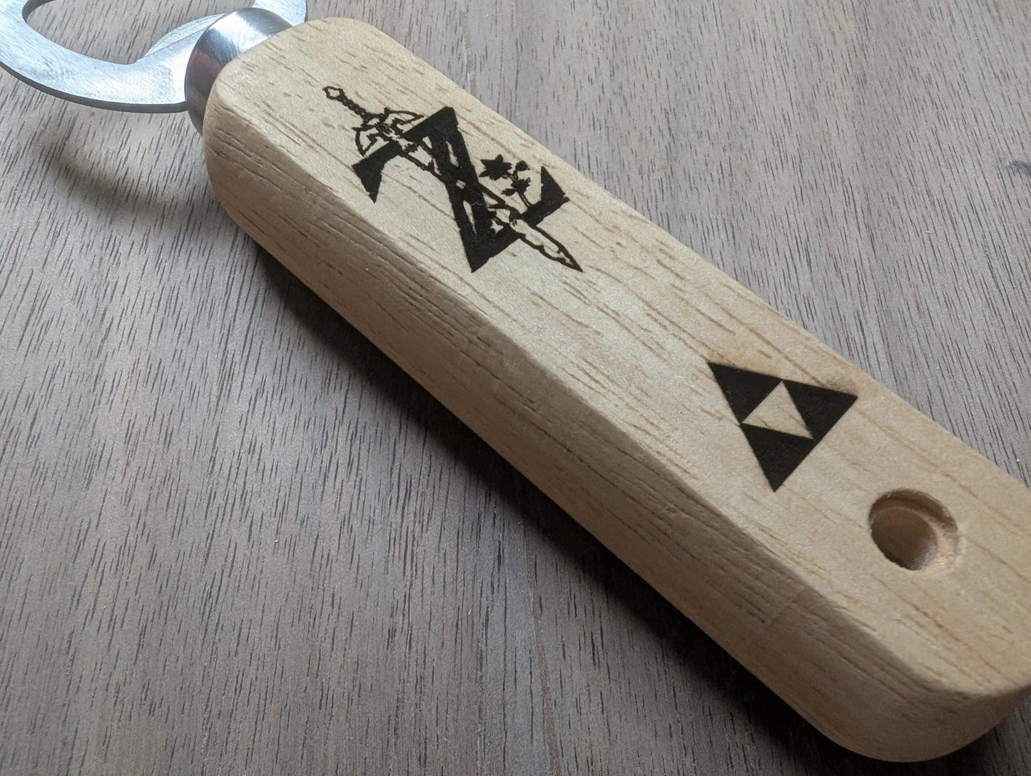Wooden bottle opener with etched video game inspired symbols on light wood handle