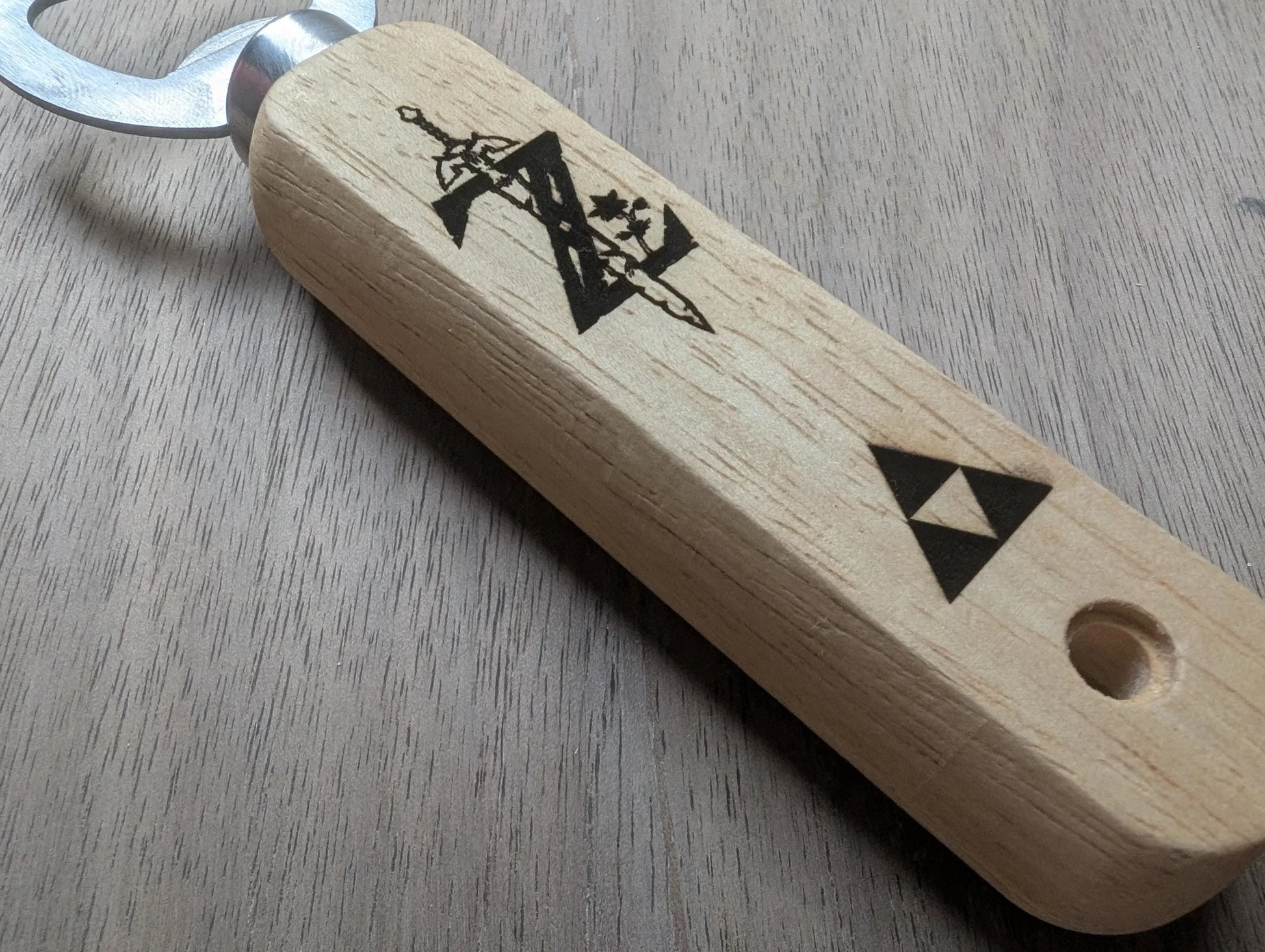 Wooden bottle opener with etched video game inspired symbols on light wood handle