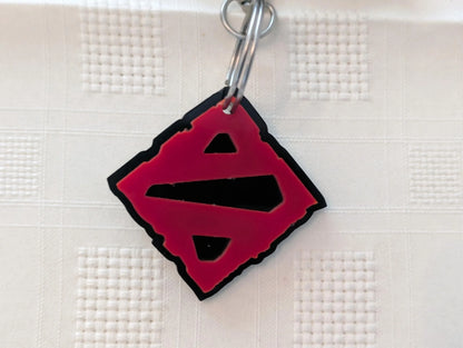 Custom acrylic keychain with red and black geometric design on textured surface.