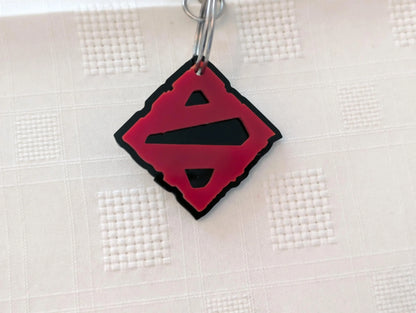 Custom black and red acrylic keychain with geometric cutout design on textured white background