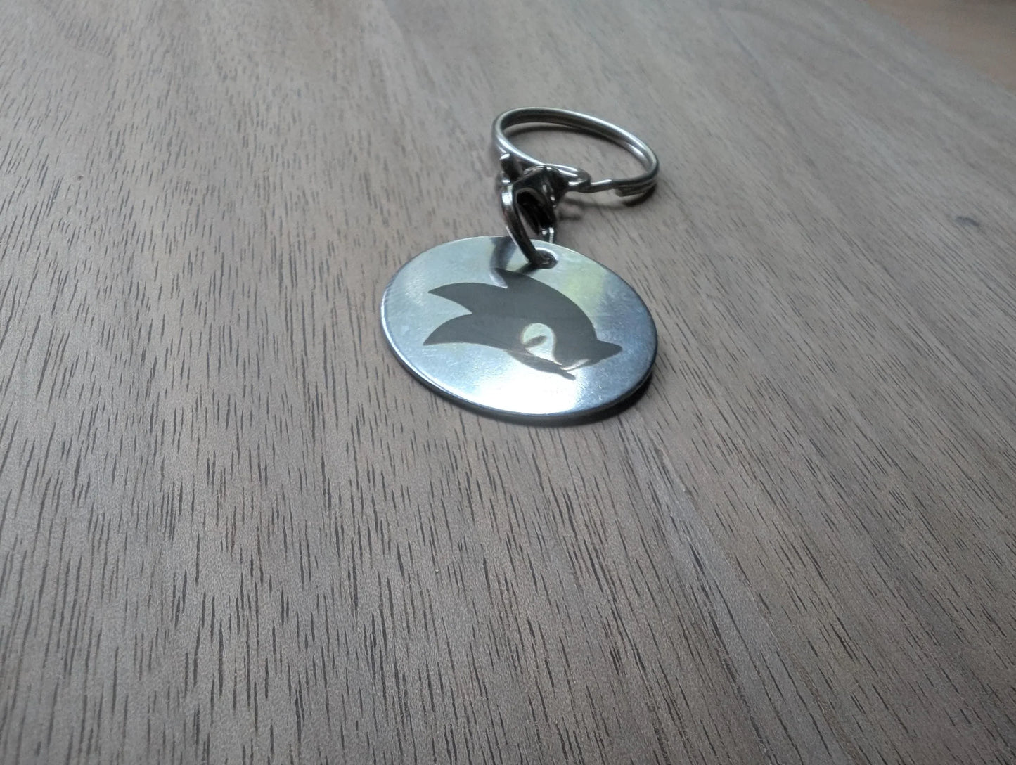 Round custom metal keychain with cut-out silhouette on wooden surface