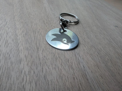 Round custom metal keychain with cut-out silhouette on wooden surface