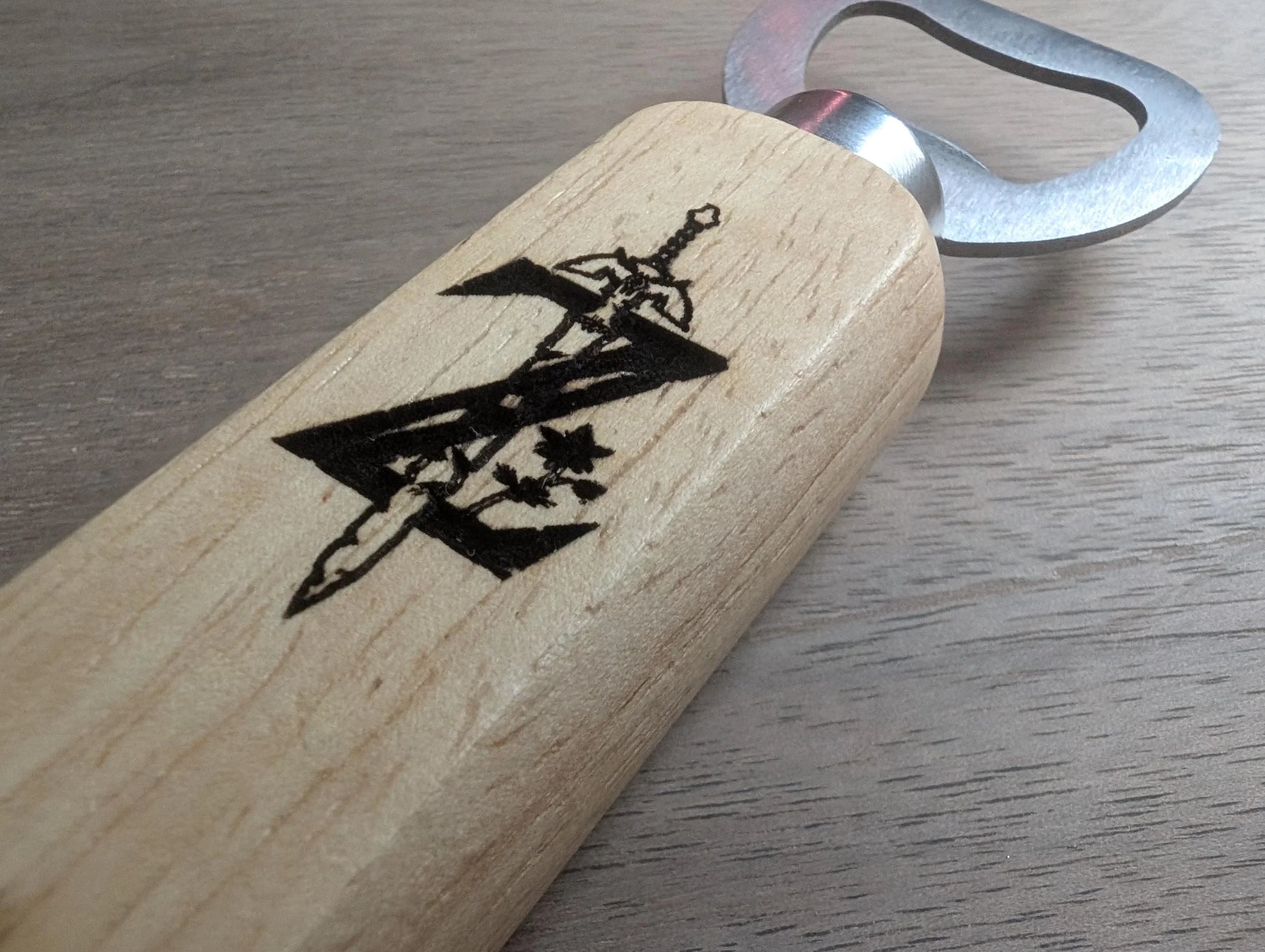 Wooden bottle opener with engraved sword and floral design on handle, metal blade, close-up